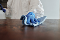 Close up image of a surface being cleaning while wearing full PPE