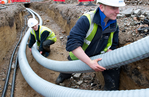 Pipes being placed in the ground by workmen.
