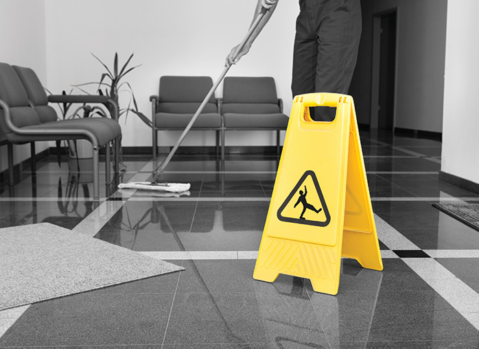 Floorbrite cleaning mopping a floor with a wet floor sign